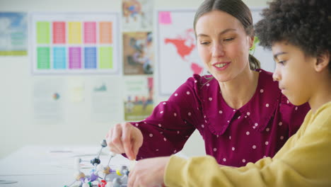 Männlicher-Student-Mit-Weiblicher-Lehrerin-Im-Klassenzimmer,-Das-Molekulare-Modelle-Im-Naturwissenschaftlichen-Unterricht-Studiert