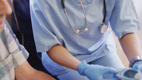 video of hands of biracial female doctor checking glucose level to caucasian senior man