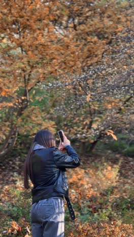 mujer tomando fotos en el parque de otoño