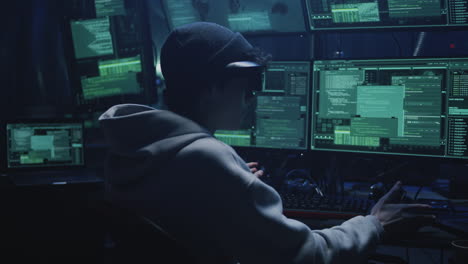 hacker working in a dark room with multiple monitors