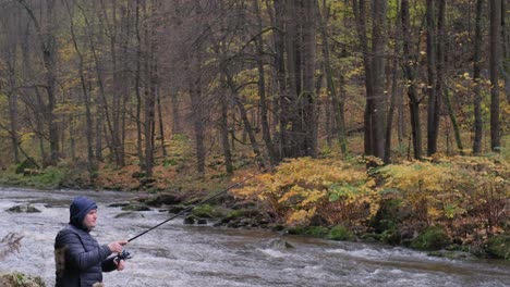 a man in a black jacket is fishing in a forest rushing river against the autumn landscape a man in a black jacket is fishing in a forest rushing river against the background of a beautiful autumn landscape fishing in a mountain river