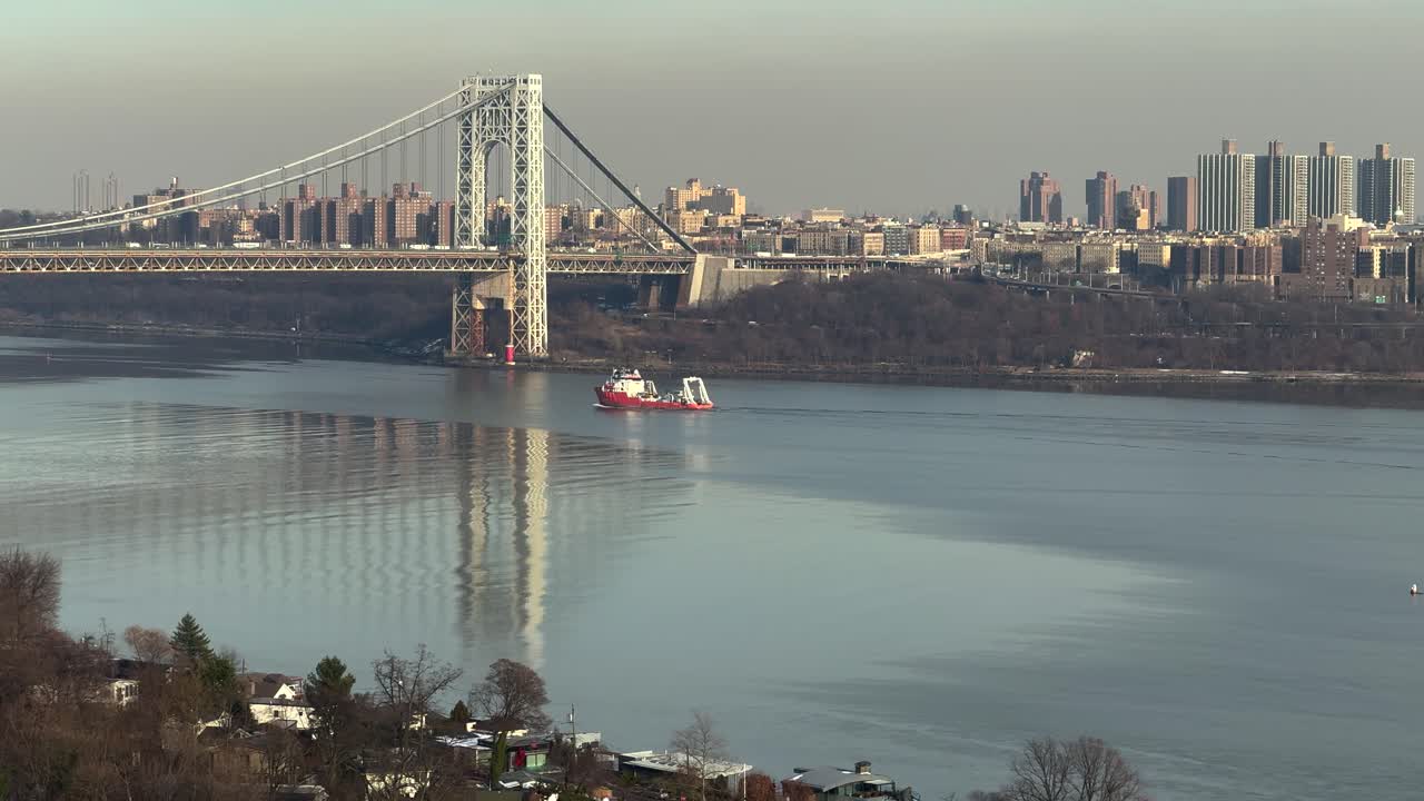 Boat sailing under George Washington Bridge on the Hudson River with New York in the background