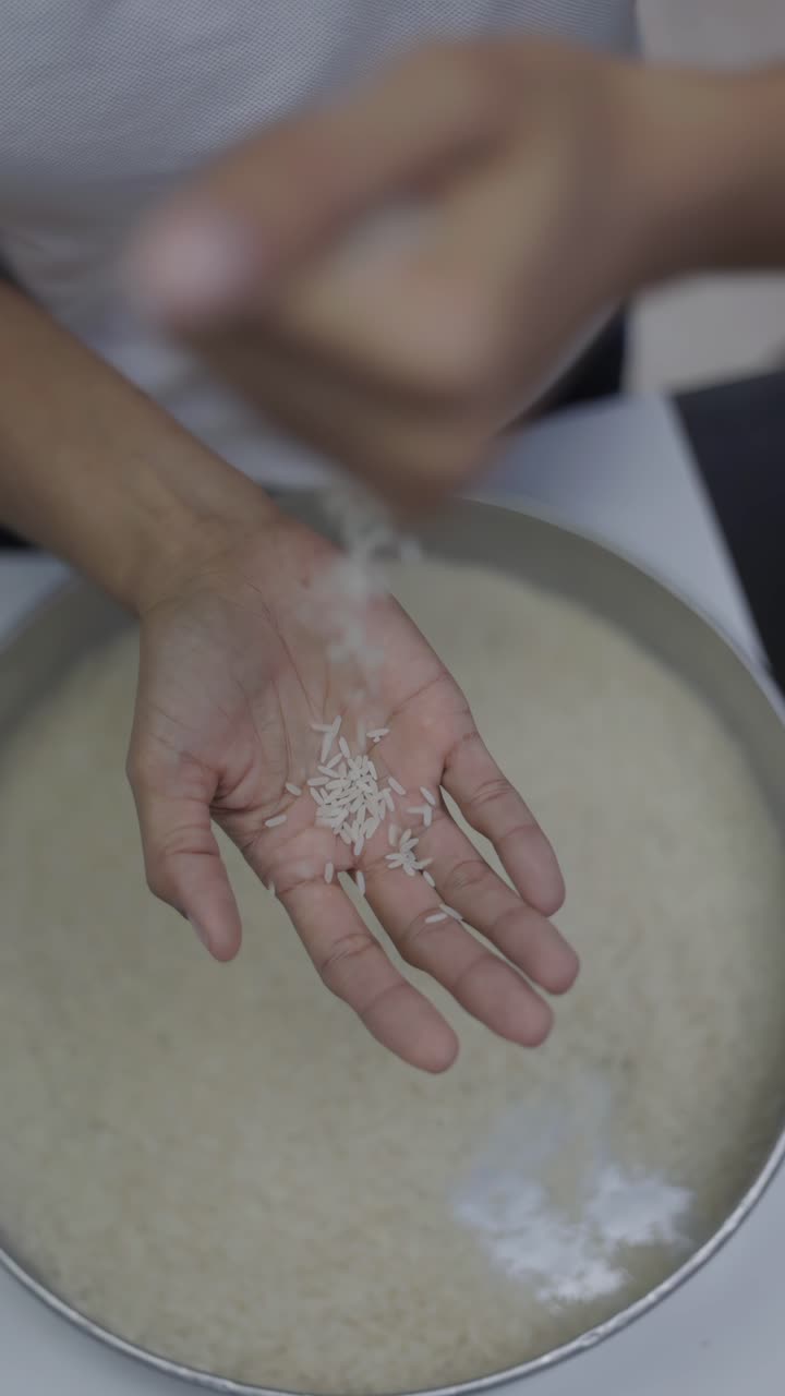Slow-motion shot of a harvester's hands dropping many processed rice grains