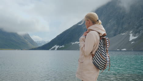 a woman looks at a high-altitude lake in norway seclusion and run away from the whole concept 4k vid