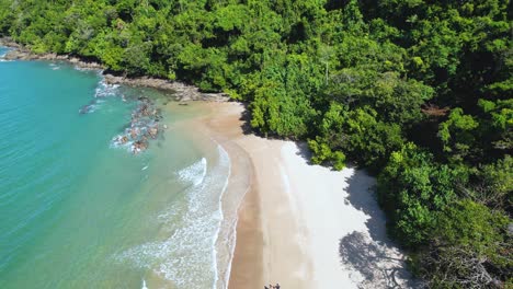 4k-Drone-video-panning-up-as-a-couple-walk-along-Etty-Bay-Beach-in-Queensland,-Australia