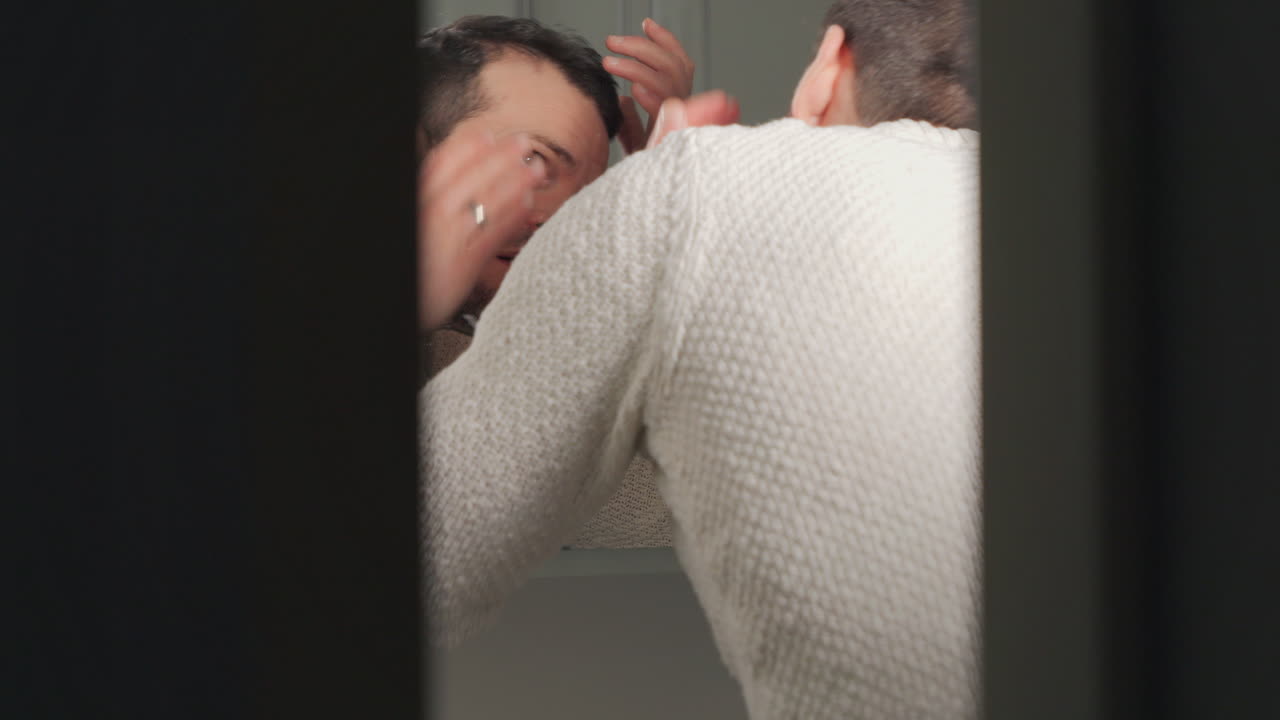 화장실 거울에서 머리카락이 물러나는 것을 조사하는 남자, 자연적인 빛에 눈에 띄는 걱정
