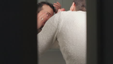 화장실 거울에서 머리카락이 물러나는 것을 조사하는 남자, 자연적인 빛에 눈에 띄는 걱정