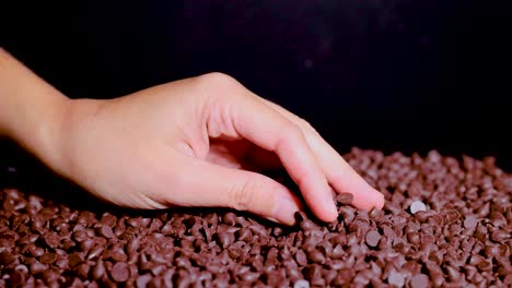 Hand sifting through chocolate chips on a surface