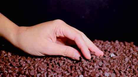 hand sifting through chocolate chips on a surface