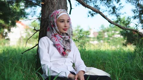 young woman in hijab relaxing in park