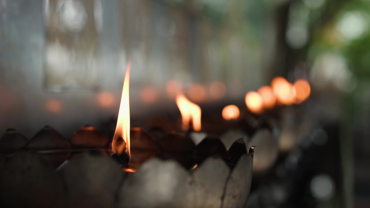 Primo piano statico di fiamme tremolanti di lampade a olio all'interno di ciotole decorative in metallo a forma di fiore di loto.