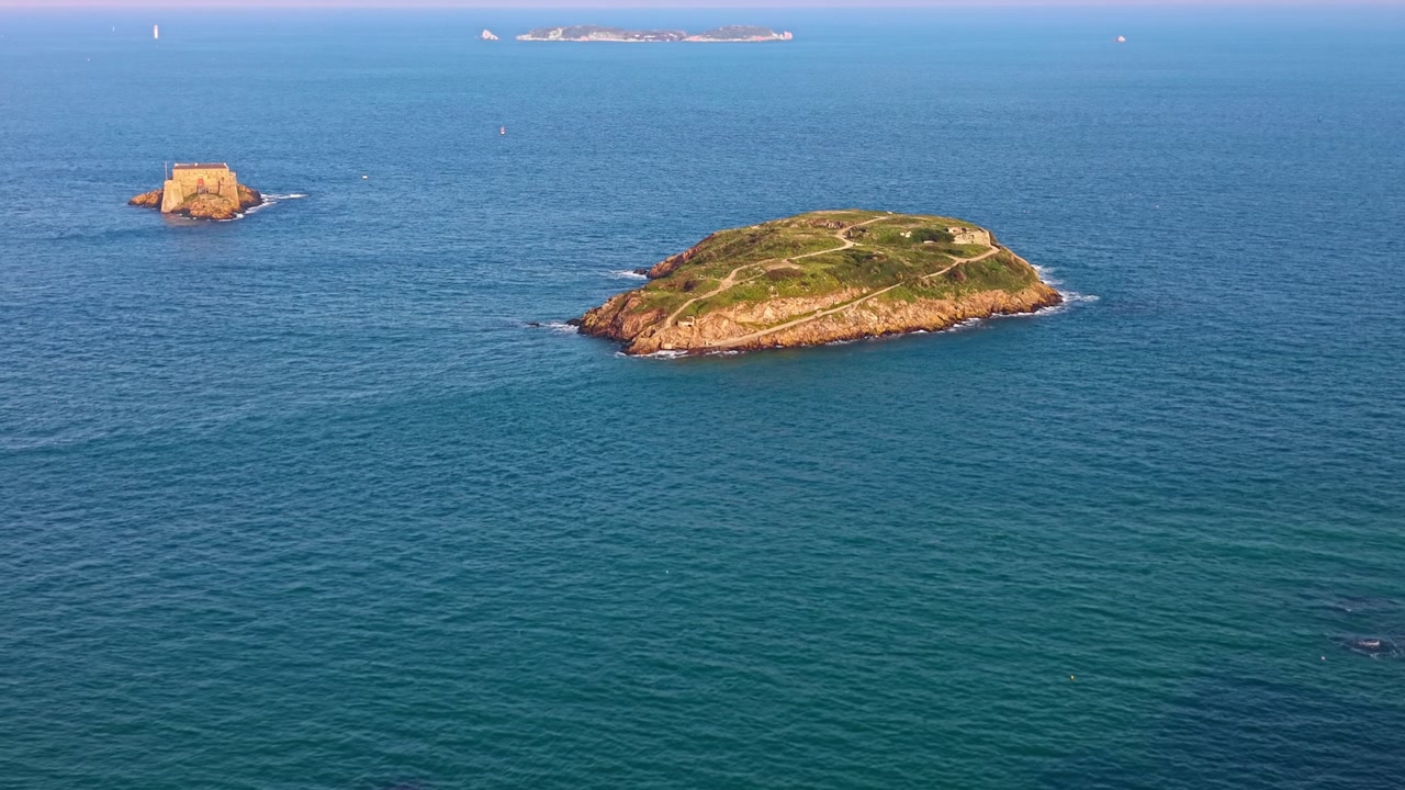 Slow drone forward movement toward Grand Be with flock of birds at start and Petit Be fort and Cezembre island in background