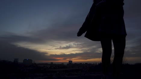 dramatic silhouette shot of a girl dancing on a rooftop while the sun is setting