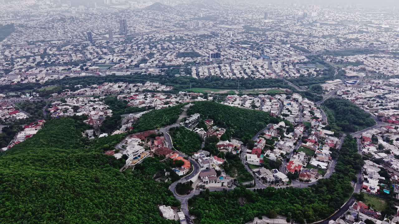 Vista aérea da cidade de Monterrey, México, com o drone avançando em direção à expansão urbana, bairros residenciais e colinas verdejantes.