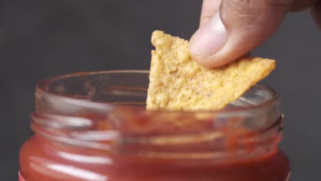 dipping tortilla chips in salsa