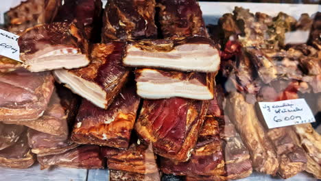 close-up of smoked meat on display at a market stall with price tags