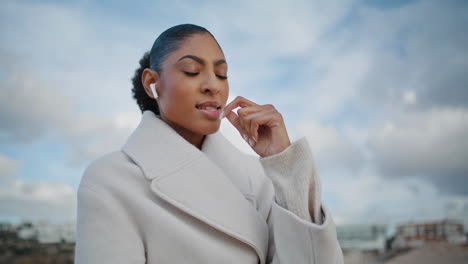 beautiful woman talking earbuds on go closeup. relaxed african american walking