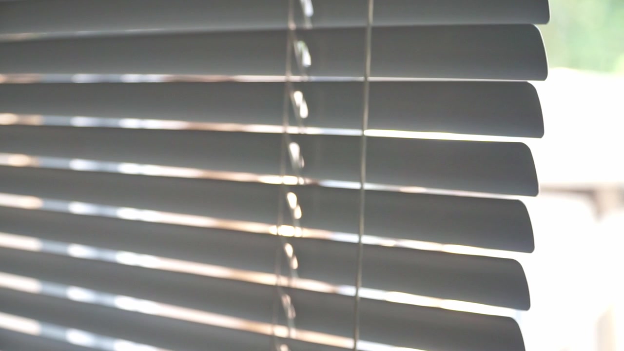 Modern blinds closing across a sunlit window, controlling brightness and visibility. Great for home décor, office environments, and architectural visuals.