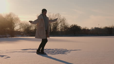 woman enjoying winter sunset on frozen lake