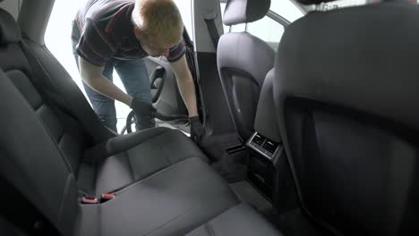 man vacuuming car interior