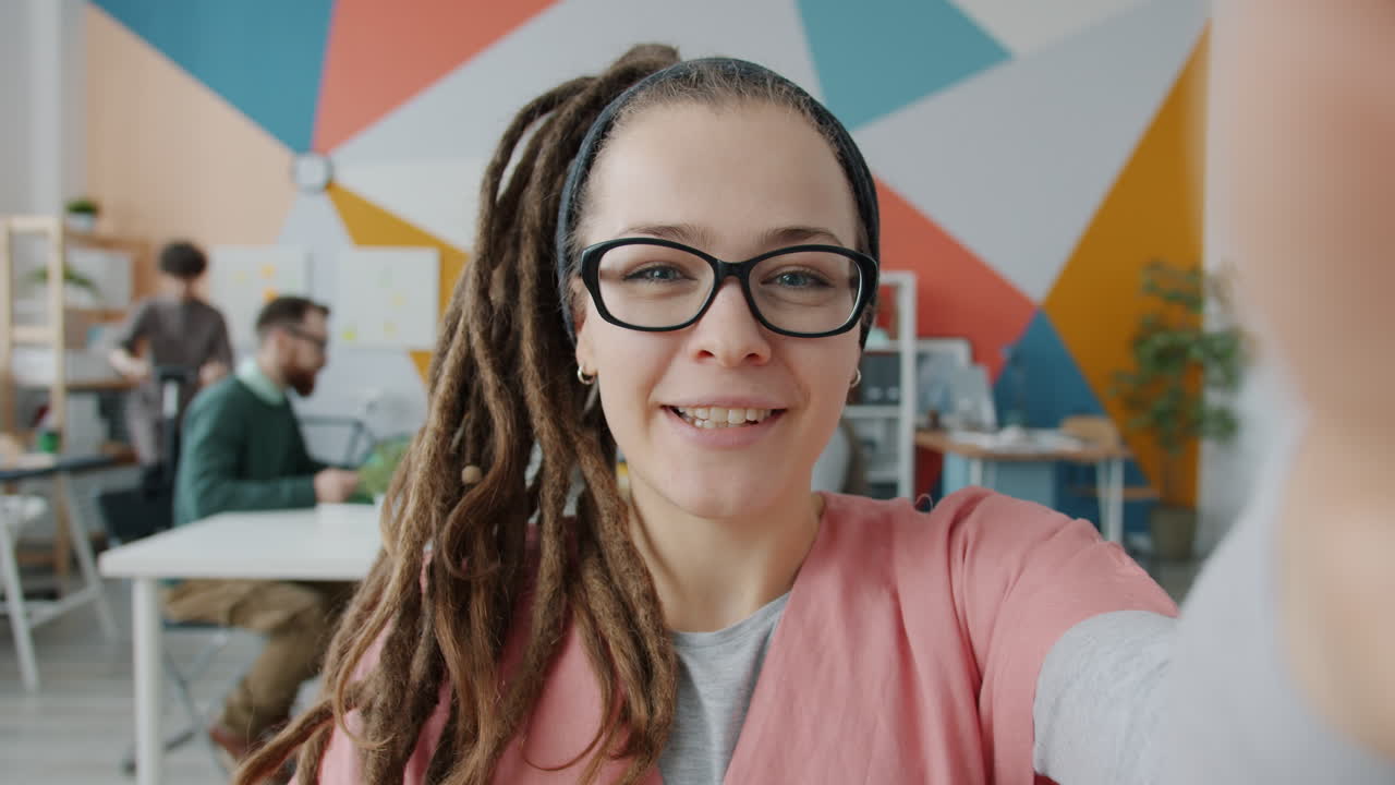Donna felice che scatta un selfie in un ufficio moderno