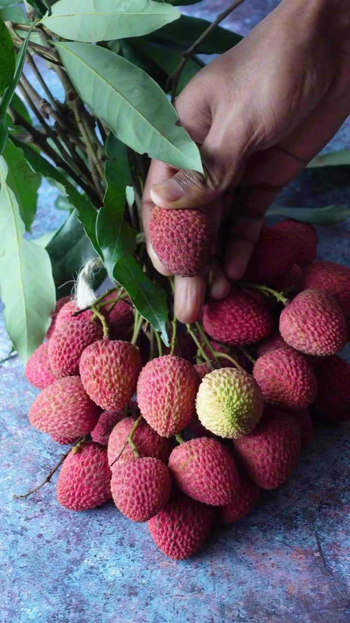 Tangan Memetik Buah Leci Segar dari Seikat