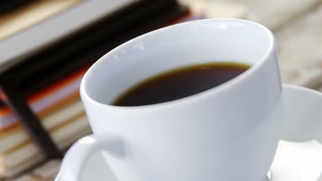 Stack-of-books,-coffee-cup,-mobile-phone-on-wooden-plank