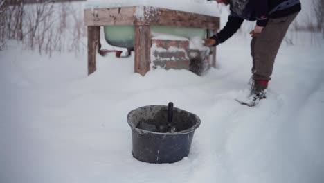 a man is clearing the snow from the bricks beneath the diy hot tub - static shot