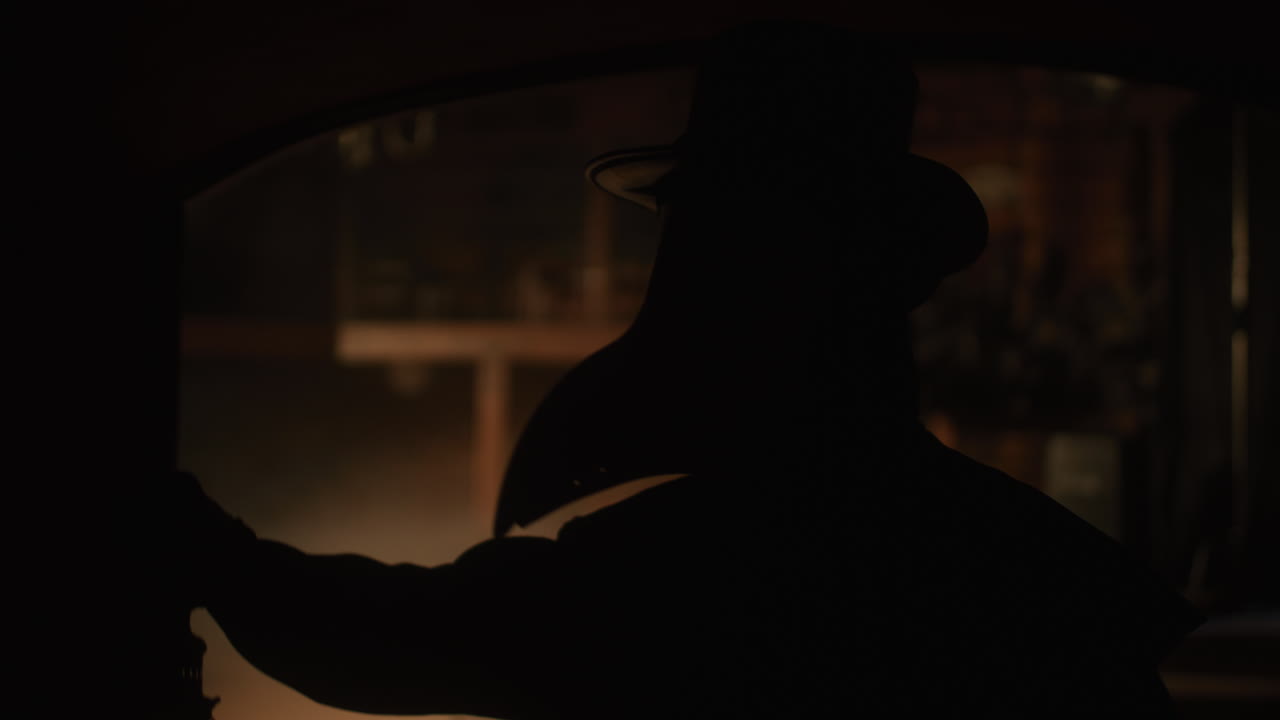 Silhouette of a Person with a Lantern in a Dark Room