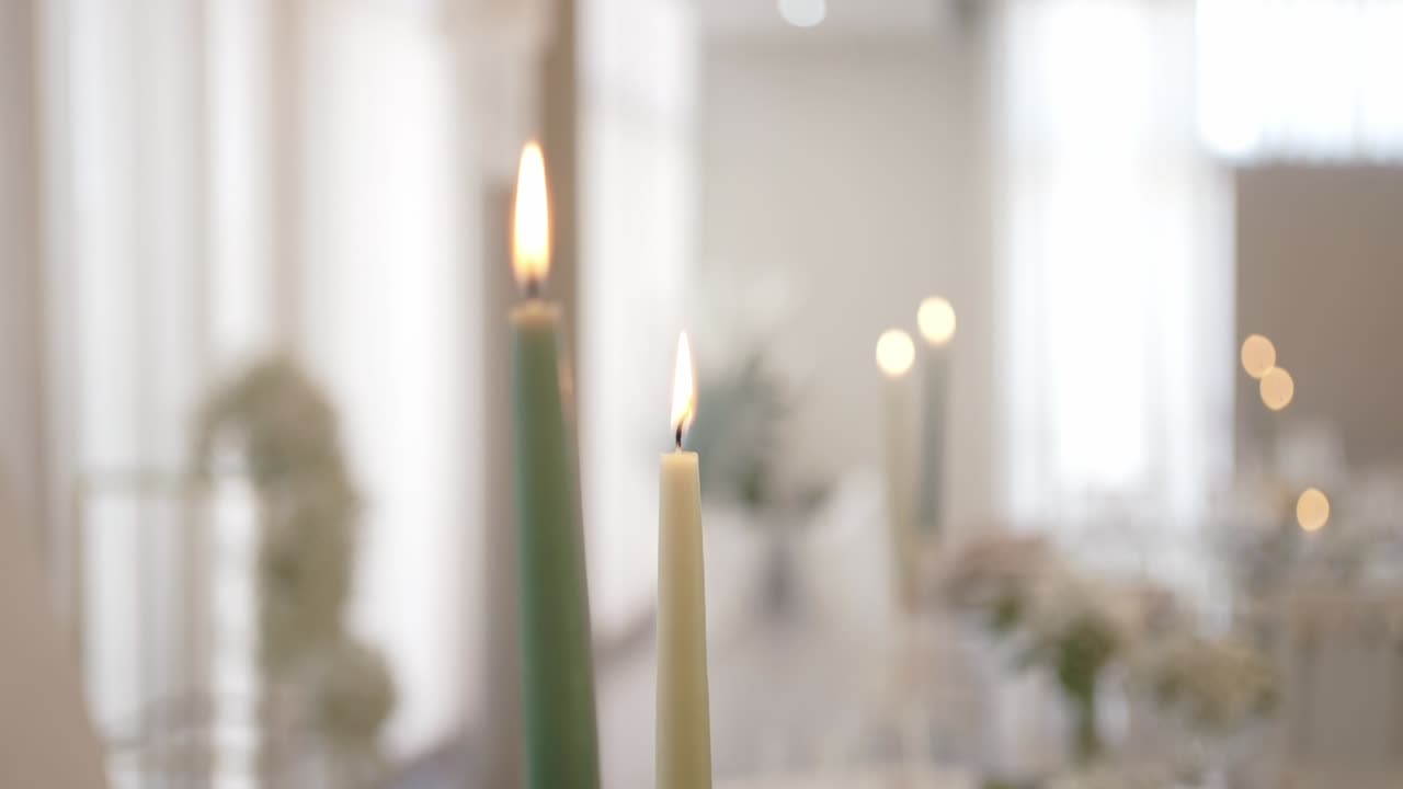 Burning candles with warm glow in softly lit elegant indoor setting