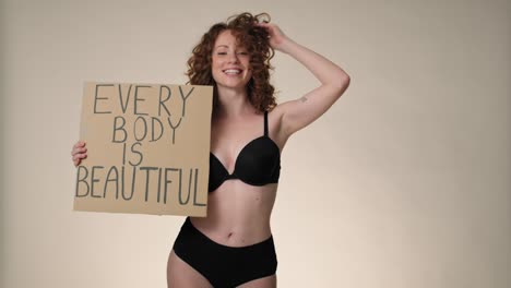 cheerful caucasian red head woman in underwear in the studio holding a banner.