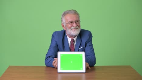 hombre de negocios barbudo y guapo contra un fondo verde.