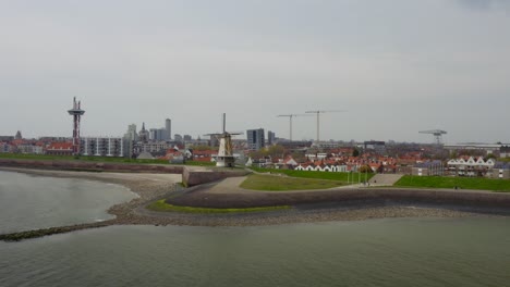 órbita-Aérea-Sobre-El-Muelle-Vacío-Con-Molino-De-Viento-Y-Panorama-De-Vlissingen-En-Los-Países-Bajos