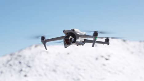 white drone hovering with snowy mountains in background