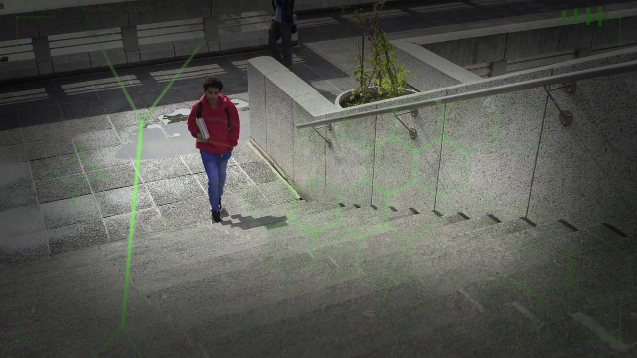 Uomo in rosso con una cartella che si avvicina alle scale, scende e poi sale, mentre un HUD di sicurezza monitora i suoi spostamenti.
