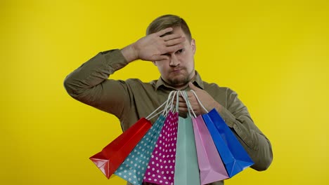 man raising shopping bags, looking satisfied with purchase, enjoying discounts on black friday