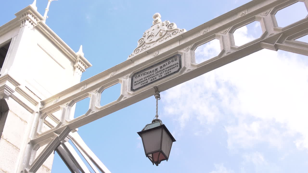 A lamp hanging above Cavenagh Bridge across Singapore river at Raffles Place, Singapore in the afternoon, blue sky