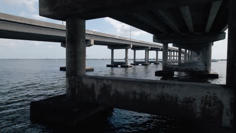 aerial shot flying through support structure of a coastal bridge