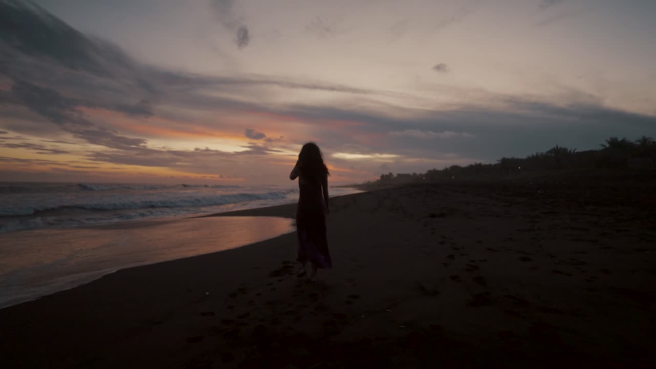 Silhouette di una donna che si rilassa in spiaggia al tramonto