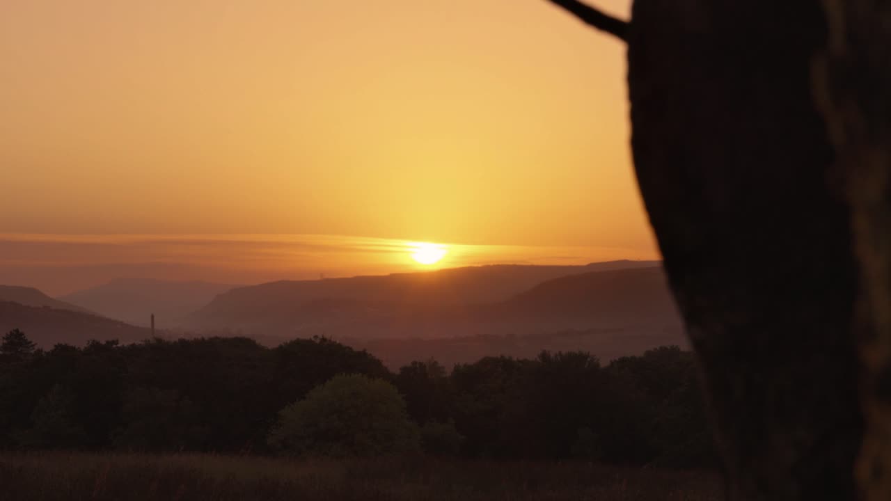 vista del amanecer sobre el nebuloso valle galés con la montaña en el fondo y el árbol en primer plano