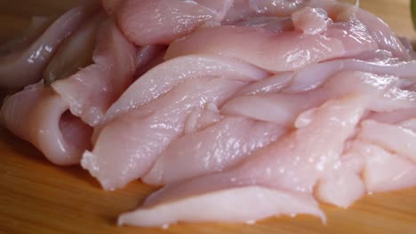 close up of raw sliced chicken breast on cutting board