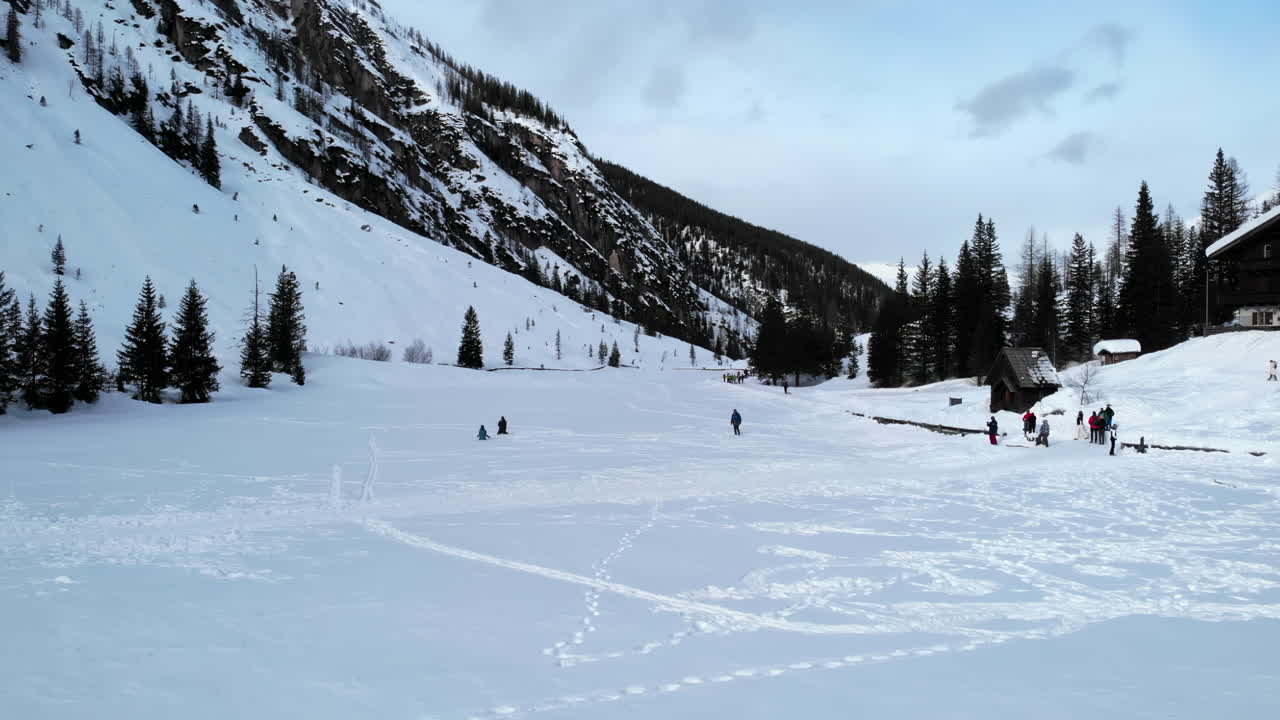 Persone che camminano e giocano in una vasta valle montana innevata