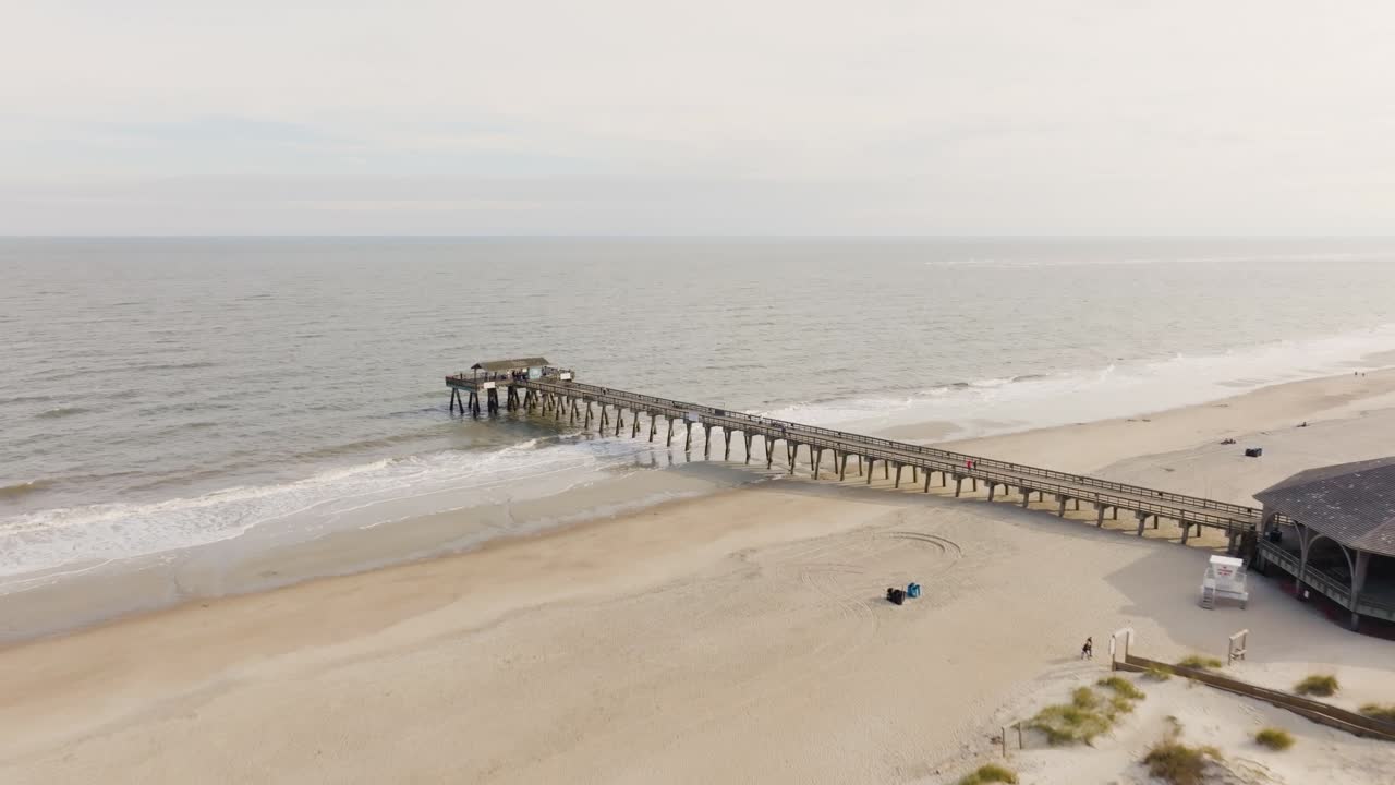 drone de una playa vacía en la isla de tybee se acerca al muelle y al océano sobre la ciudad