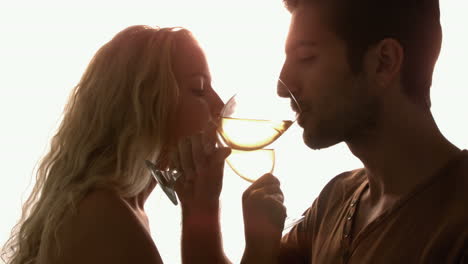 Couple-drinking-together-with-crossed-arms-against-sunlight