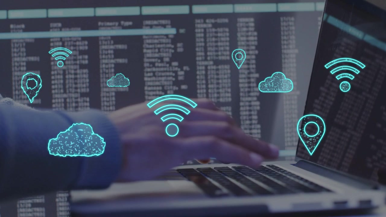 IT-professionel taster på bærbar computers tastatur, visualiserer Wi-Fi-, sky- og lokationsikoner, der lægger sig over hænderne.
