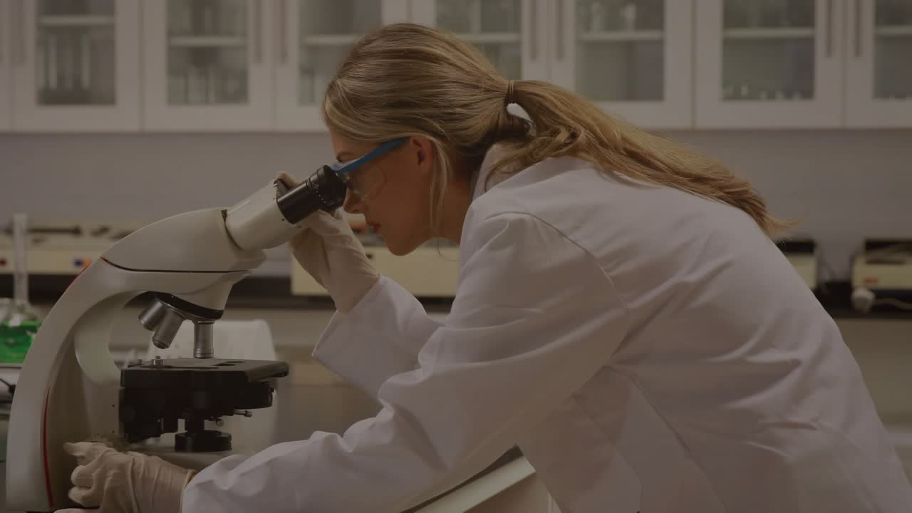 Lab scientist peering into microscope and adjusting knobs while math notes appearing, showing data