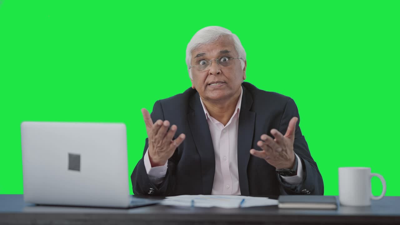 Angry senior Indian businessman shouting on someone Green screen