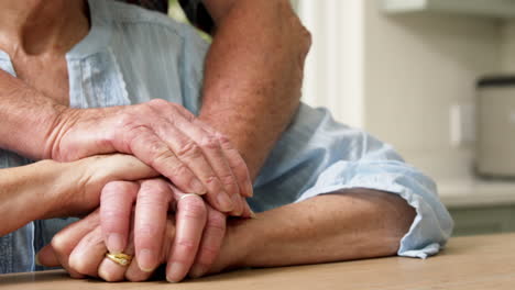 una pareja de ancianos con las manos una sobre la otra.