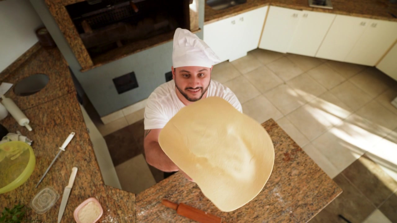 Chef esperto lancia con maestria l'impasto della pizza in aria, creando la base perfetta per una pizza fresca