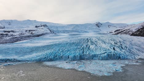 Aerial-landscape-view-of-a-glacier-with-textured-ice-formations,-in-Iceland,-at-dusk